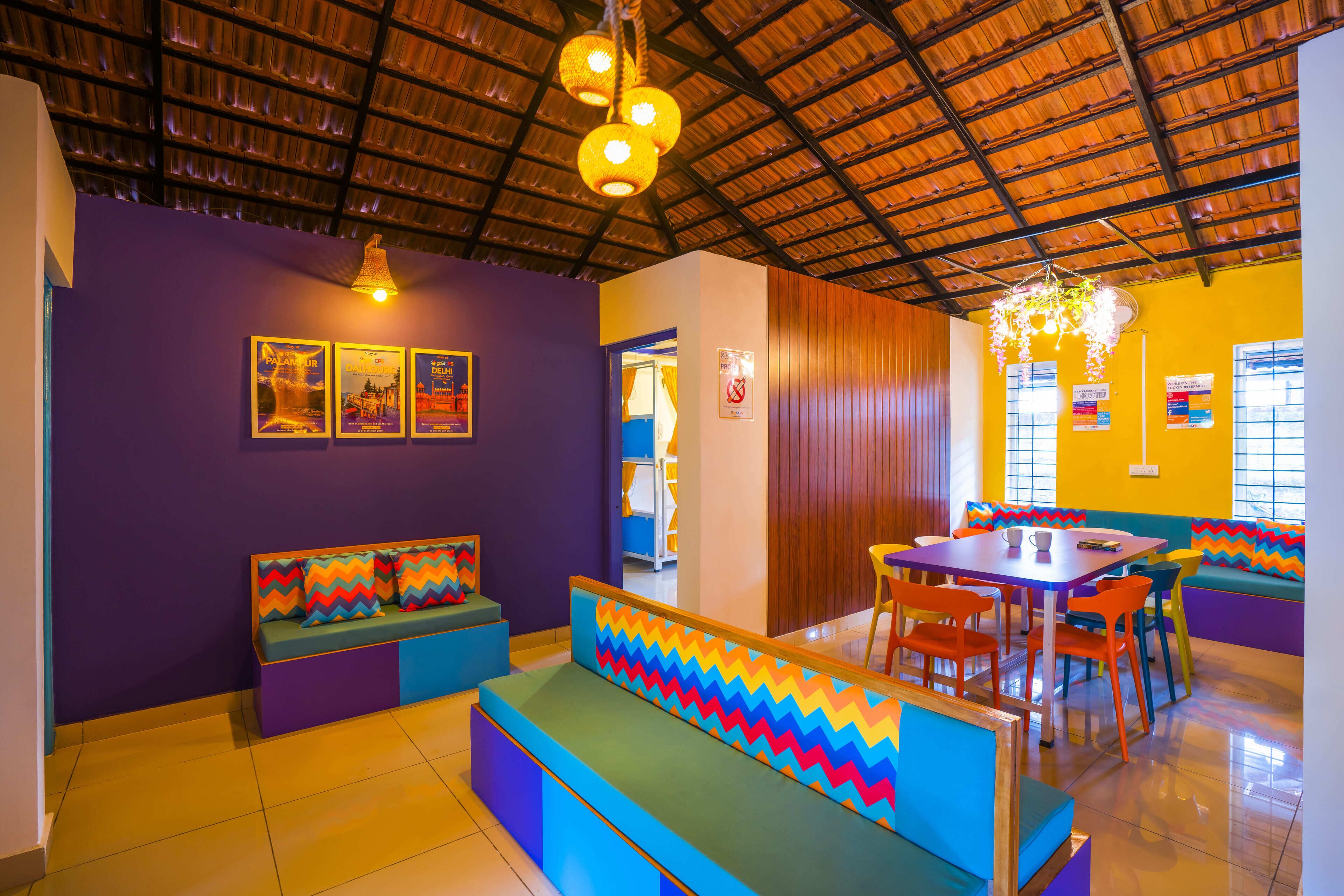 A vibrant restaurant interior with colorful seating, a high ceiling, and decorative lighting.