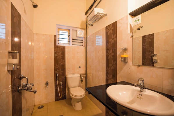 A bathroom with a toilet, sink, shower, and a window. - goSTOPS Coorg (Madikeri)