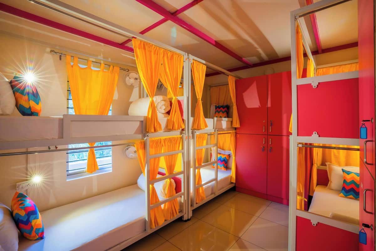 A room with bunk beds, orange curtains, and a red wardrobe.