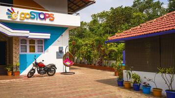A building with a 'goSTOPS' sign, a motorcycle parked outside, and potted plants along the pathway.