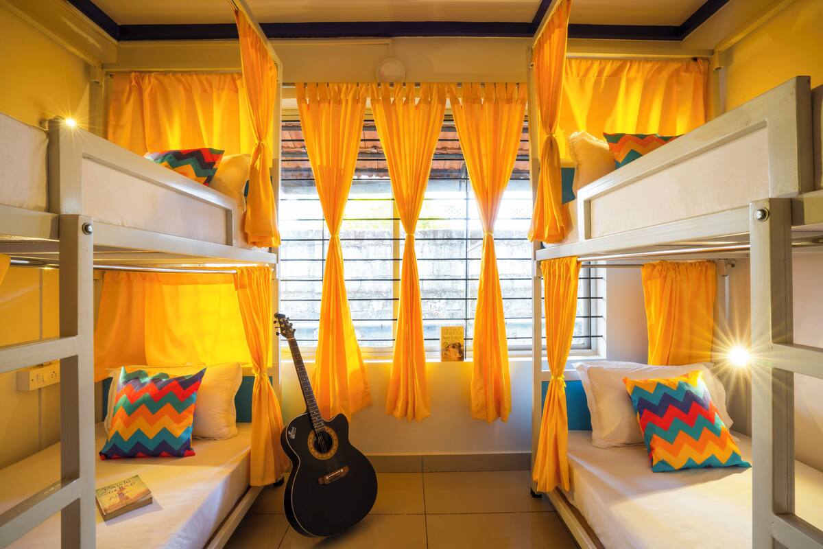 A room with bunk beds, a guitar, and yellow curtains.
