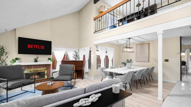 Ein geräumiges Wohnzimmer mit Kamin, Essbereich und einem Fernseher, der "NETFLIX" zeigt.