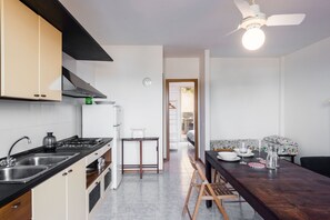 Køleskab, ovn, køkkentøj/tallerkener/redskaber, spisebord