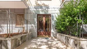 Une cour avec une porte en bois, des clôtures en métal et un chemin en béton.