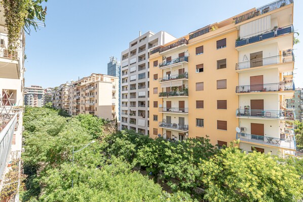 Un immeuble résidentiel à plusieurs étages, doté de balcons, avec un ciel dégagé et entouré de verdure.