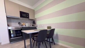 A compact kitchen with a built-in oven, microwave, and a dining area with a table and chairs.