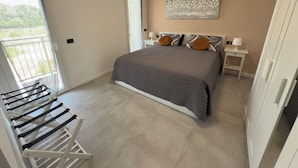 A bedroom with a bed, a window, a door, and a towel rack.