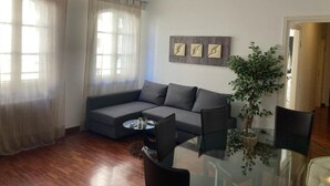 A living room with a grey sectional sofa, a glass coffee table, and a potted plant. - Accomodo MIT51 Trivano Cenisio  (Milan)
