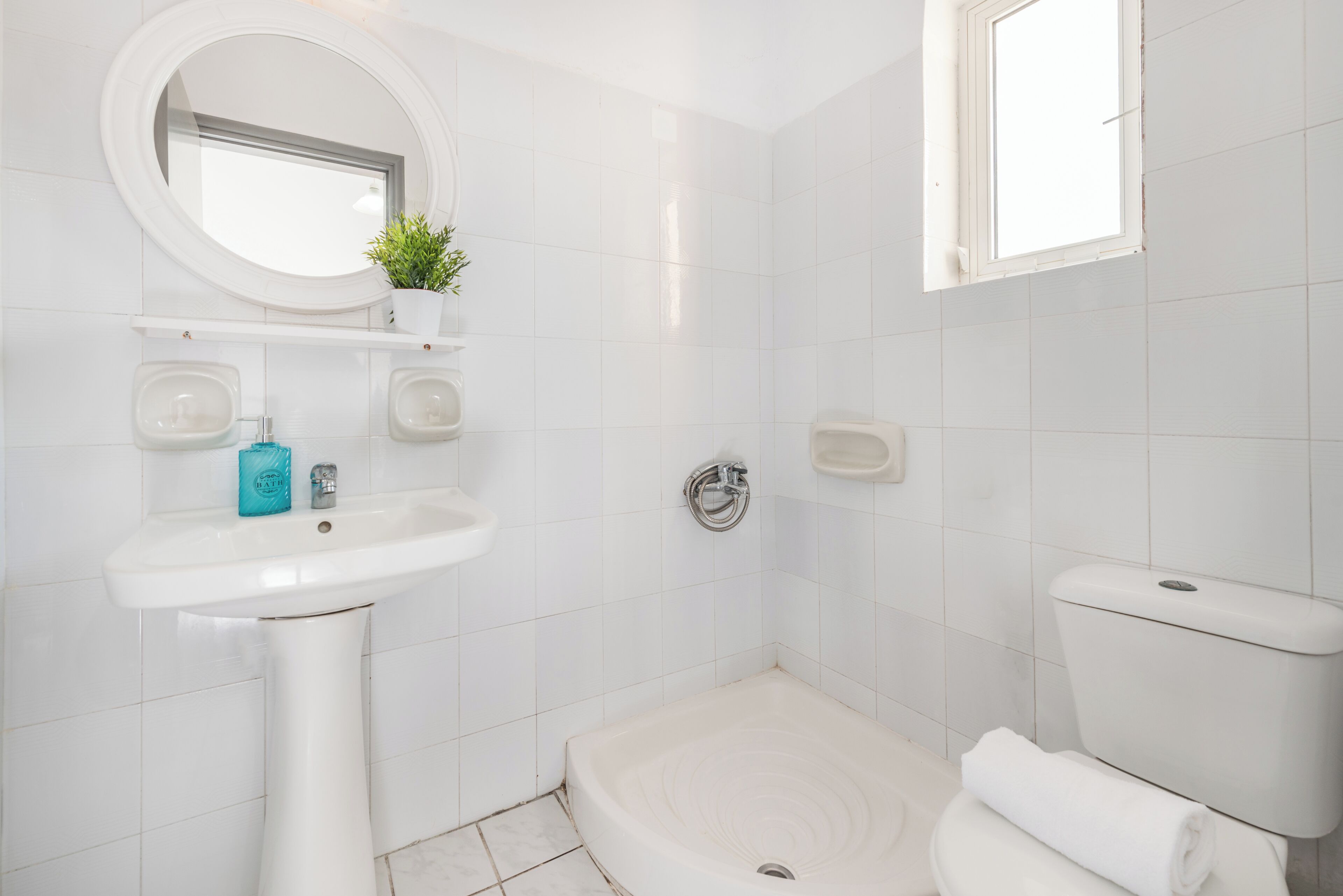 A modern bathroom with a pedestal sink, a toilet, and a shower.
