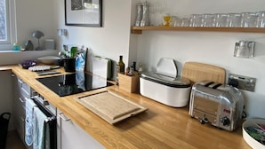 A kitchen with a wooden countertop, a toaster, a blender, a kettle, and a coffee maker.