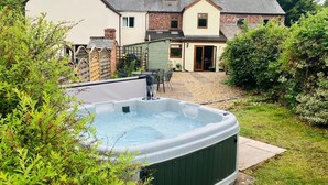 A hot tub in a backyard with a house in the background. - Cosy 18th century cottage. Pet friendly. Absolute tranquility! (Mitcheldean)