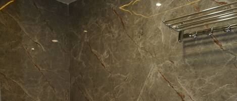 A modern bathroom with a freestanding bathtub, marble walls, and a black countertop.