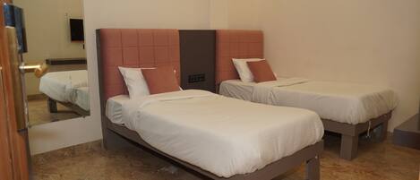 Habitación de hotel con dos camas, cada una con cabecera y almohadas.