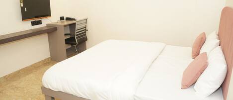 A bedroom with a bed, a desk, a chair, and a television.