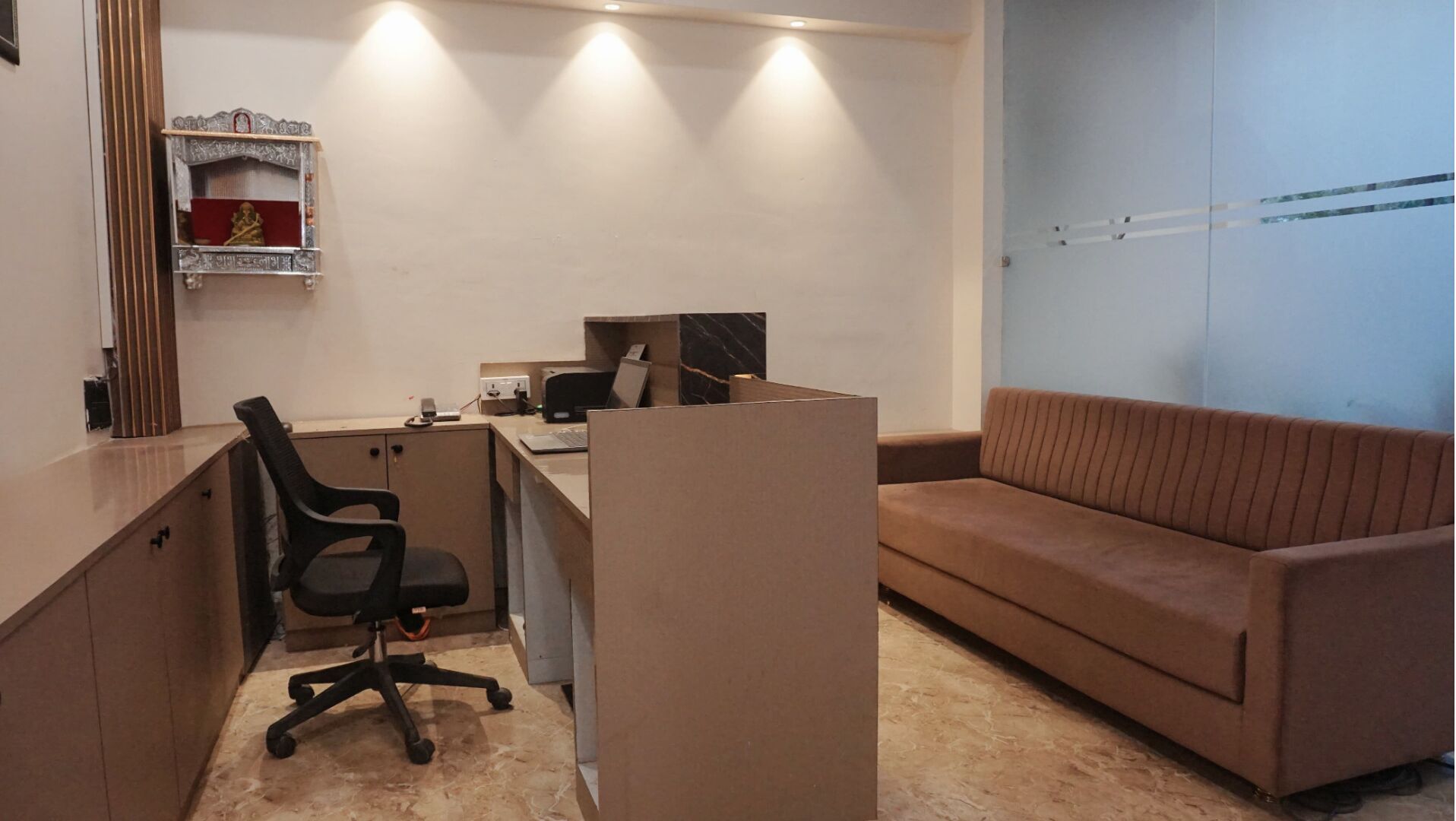A modern office space with a desk, office chair, and a sofa.