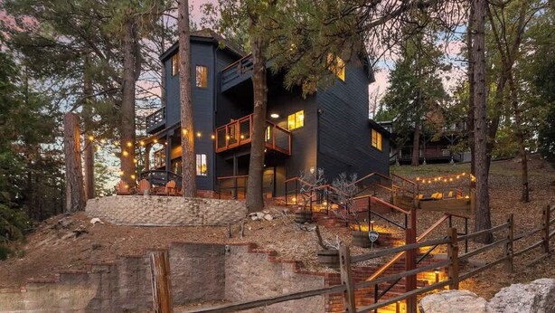 A modern house with a stone staircase, wooden deck, and string lights.