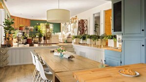 A modern kitchen with wooden countertops, white cabinetry, and a dining area with a wooden table and chairs.