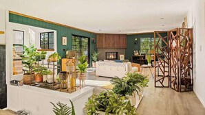 A spacious living area with a fireplace, multiple seating options, and abundant indoor plants.
