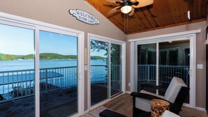 A spacious balcony with a view of a lake, a ceiling fan, and a welcome sign. - Newly Listed! Lakefront Home Private Dock with Huge Views (Camdenton)