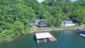 A lakeside property with two houses, a dock, and a boat. - Newly Listed! Lakefront Home Private Dock with Huge Views (Camdenton)