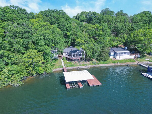 A lakeside property with two houses, a dock, and a boat. - Newly Listed! Lakefront Home Private Dock with Huge Views (Camdenton)