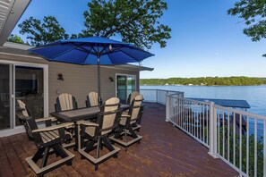 A deck with a table and chairs, a blue umbrella, and a view of a lake. - Newly Listed! Lakefront Home Private Dock with Huge Views (Camdenton)