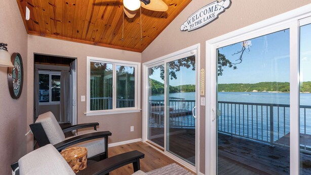 A room with a view of a lake, a ceiling fan, and a 'Welcome to the Lake' sign. - Newly Listed! Lakefront Home Private Dock with Huge Views (Camdenton)