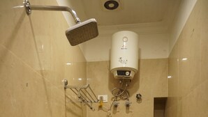 A bathroom with a shower, toilet, and a water heater. - The Premier Inn (Kolkata)