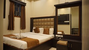 A hotel room with a large bed, a nightstand, a mirror, and a wardrobe. - The Premier Inn (Kolkata)