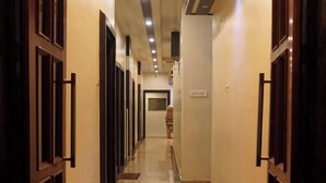 A long, narrow hotel corridor with a polished marble floor and wooden doors on both sides. - The Premier Inn (Kolkata)