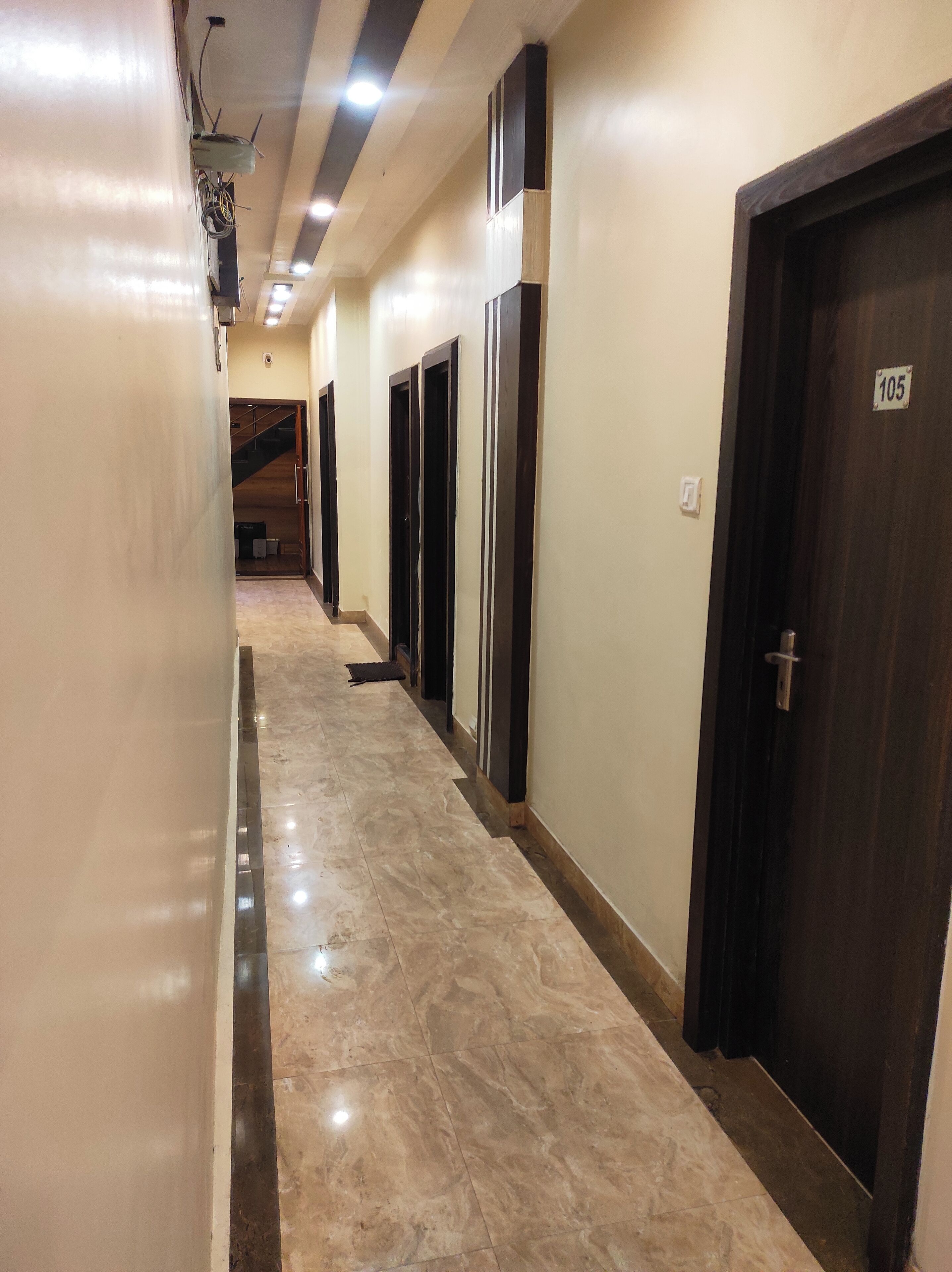 A corridor with marble flooring, dark wooden doors, and a staircase at the end.