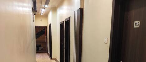 A corridor with marble flooring, dark wooden doors, and a staircase at the end.