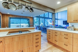 A modern kitchen with wooden cabinets, a large window, and a view of the outdoors.