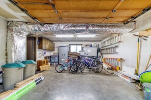 Garagem com bicicletas, materiais de construção e teto parcialmente isolado.
