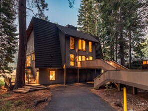 A modern two-story building with a staircase leading to the entrance, surrounded by trees.