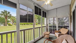 A covered outdoor area with wicker furniture, large windows, and a ceiling fan. - Myrtlewood Unit 103 - Golf Area! (Myrtle Beach)