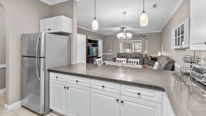 A modern kitchen with white cabinetry, a stainless steel refrigerator, and pendant lighting. - Myrtlewood Unit 103 - Golf Area! (Myrtle Beach)