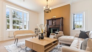 A living room with a fireplace, a sofa, a coffee table, and a bench. - Spacious, Cosy Cotswolds Farmhouse with Annex (Tewkesbury)