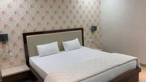 A bedroom with a bed, two bedside tables, and floral wallpaper. - Hotel Crown Resort (Satna)