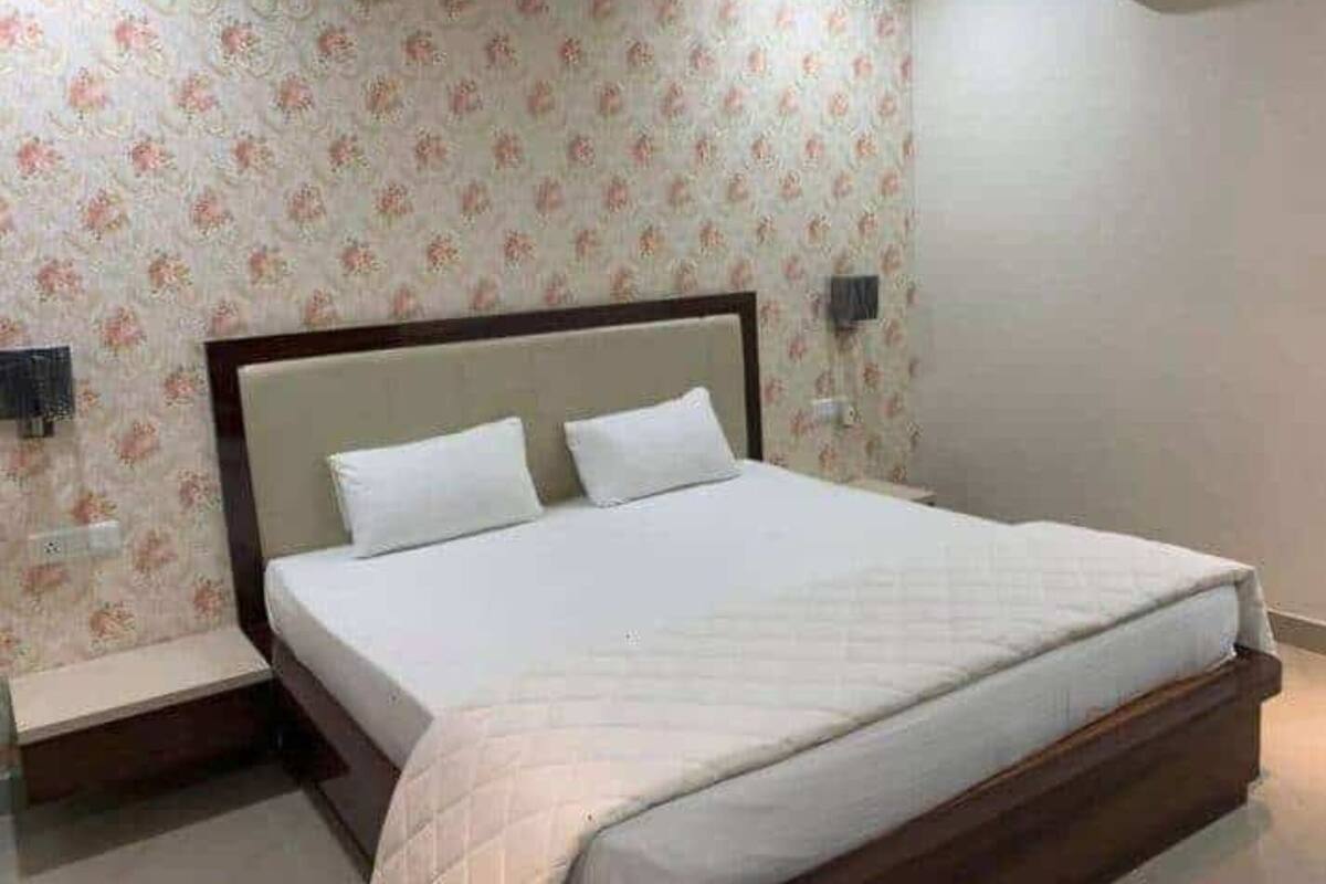 A bedroom with a bed, two bedside tables, and floral wallpaper.