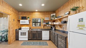 A kitchen with wooden paneling, white appliances, and a window with a view.