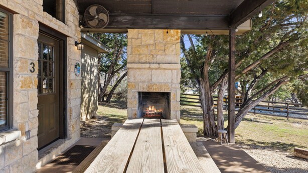A stone building with a fireplace, wooden deck, and outdoor seating area.