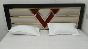 A bed with a headboard featuring a geometric design and two white pillows. - Awadh Biharee Inn (Faizabad)