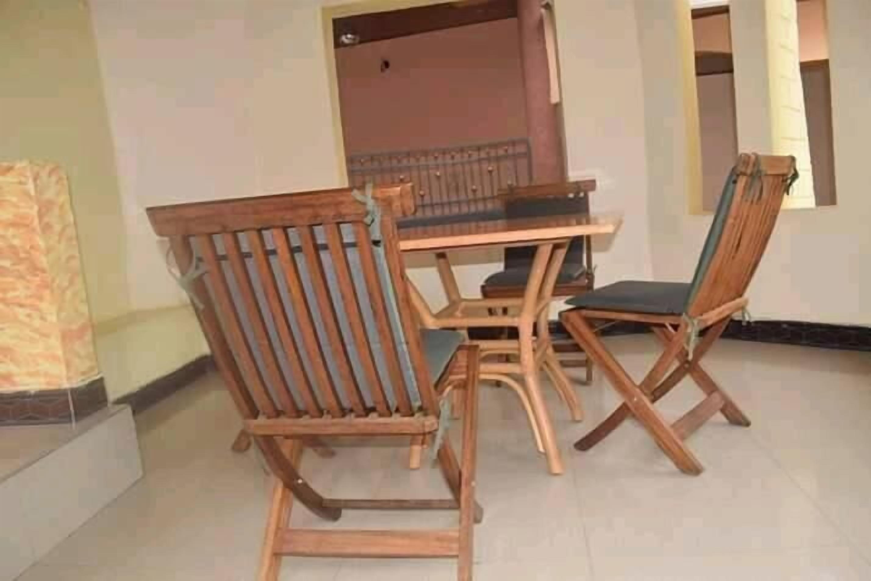 Een eethoek met een houten tafel en stoelen, een betegelde vloer en een doorgang naar een andere kamer.