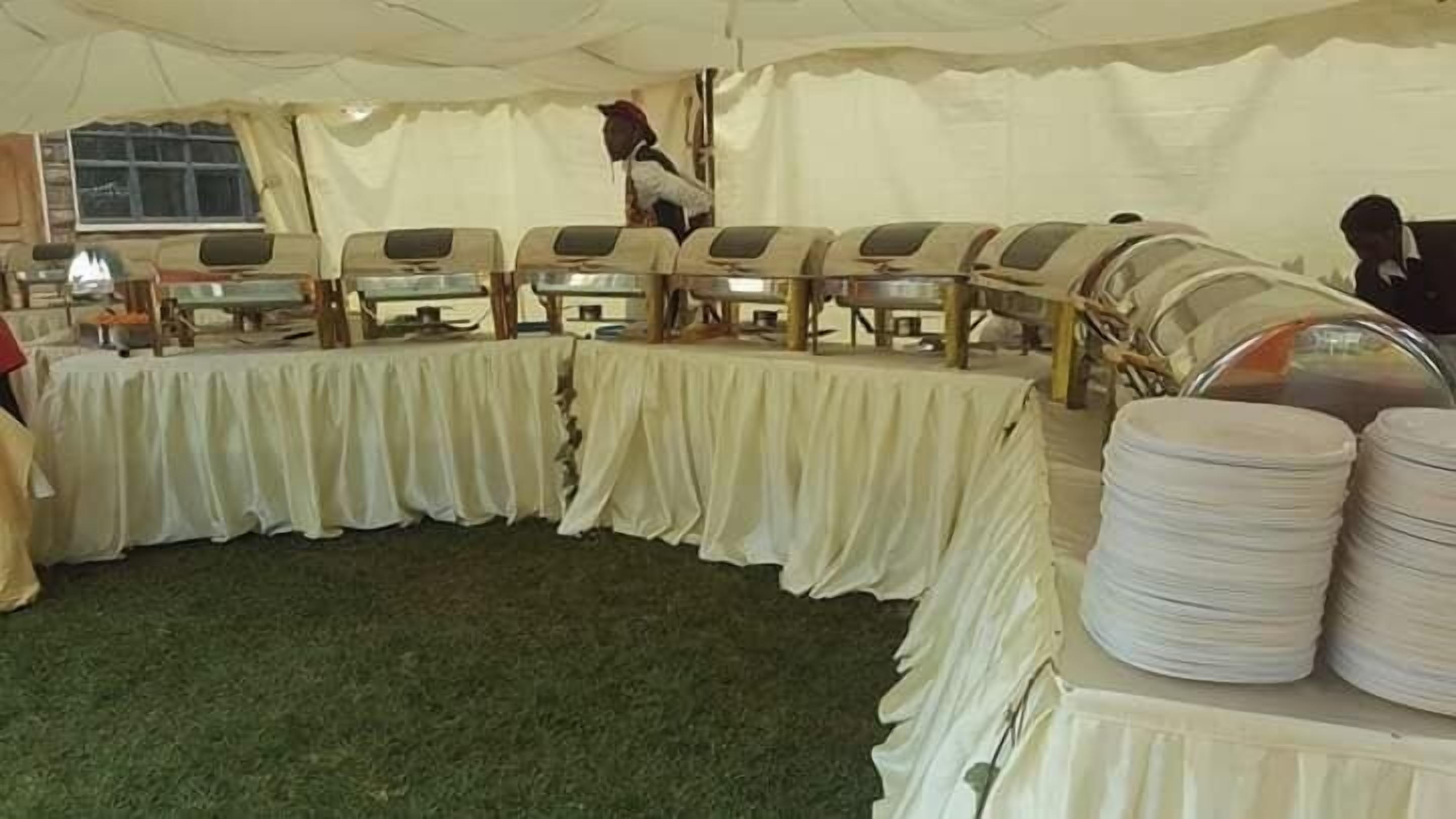 Un espace événementiel aménagé sous une tente, avec des tables recouvertes de nappes blanches et doté de points de service pour la restauration.