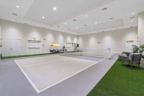 A tennis court with a net, seating area, and a reception desk. - Luxury 3BR Key Largo Townhome | Ocean & Pool Views (Key Largo)