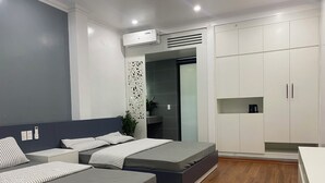 Une chambre moderne avec deux lits, une armoire et un coin cuisine.