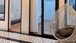 Un intérieur moderne avec un fauteuil suspendu, un sol à motifs et une vue à travers une porte vitrée.