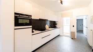 Une cuisine moderne avec des meubles blancs, un four noir et un revêtement mural noir.