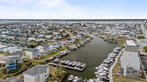 Un port de plaisance où sont amarrés de nombreux bateaux, entouré de maisons et avec un pont en arrière-plan.